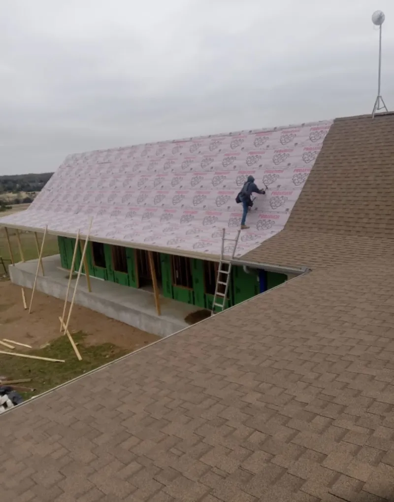 Worker preparing underlayment for a metal roof installation in Hamilton